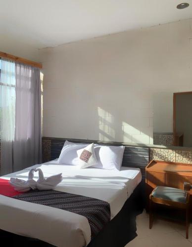 a bedroom with a bed with white sheets and a desk at Kusma Hotel Bandungan Semarang in Semarang