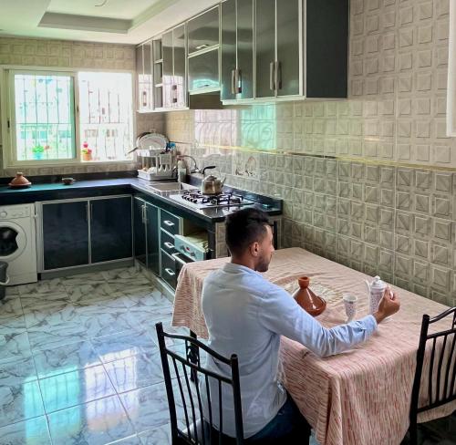 a man sitting at a table in a kitchen at M'a Raffiné appartement 2 in Casablanca