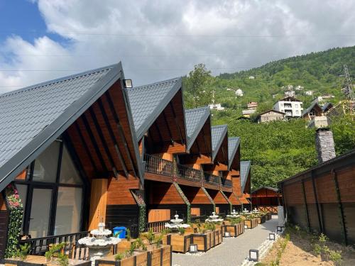 a row of wooden buildings with a mountain in the background at Aquarium BUNGALOW UZUNGÖL in Uzungol