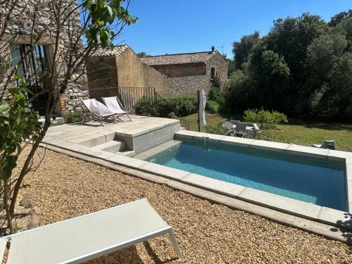 uma piscina num quintal com duas cadeiras em Mas Saint-Ferdinand - maison avec piscine em La Capelle-et-Masmolène