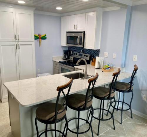 a kitchen with a island with four bar stools at Gulf Shores Surf & Racquet Club 212A in Gulf Shores