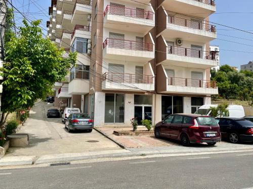 a building with cars parked on the side of a street at Beach Apartments Durres in Durrës