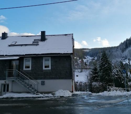 Una casa con nieve en el techo. en Große Ferienwohnung am Rennsteig, en Neuhaus am Rennweg