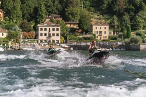 two people riding on jet skis in the water at Domus Plinii 1792 Suites in Faggeto Lario 