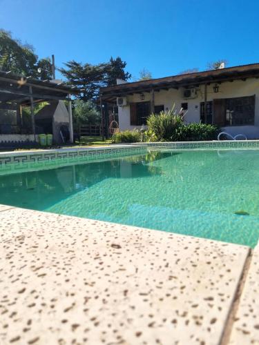 - une piscine d'eau bleu clair en face d'une maison dans l'établissement Tordillo B&B, à Chascomús