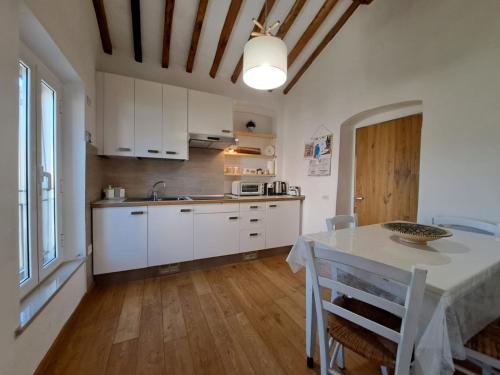 una cocina con armarios blancos y una mesa con sillas. en Wishlist - Casa Vacanze, en Campiglia Marittima