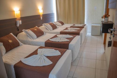 Un grupo de 4 camas en una habitación en Hotel do Reinildo I, en Cachoeira Paulista