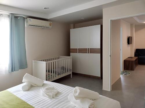 a bedroom with a crib and a bed with white sheets at Villa LunaSole Samui in Koh Samui 