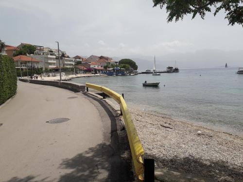 a beach with a yellow railing next to the water at Apartments Lilly in Ðenovići
