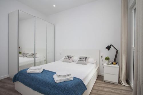 Dormitorio blanco con cama blanca y espejo en Quart Apartment, en Valencia