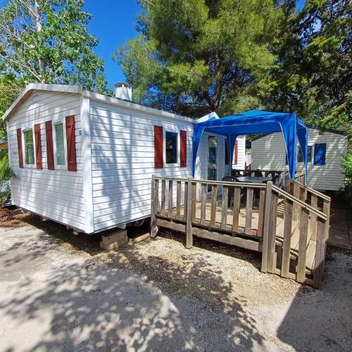 une petite maison blanche avec une bâche bleue dessus dans l'établissement Camping les Salisses - Vias Plage - Mobilhome, à Vias