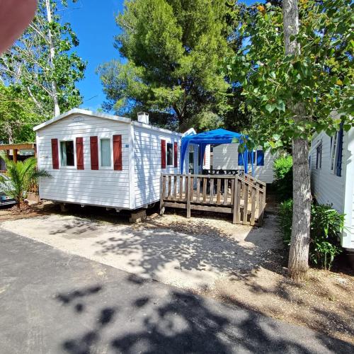une maison blanche avec un porche et une tente bleue dans l'établissement Camping les Salisses - Vias Plage - Mobilhome, à Vias