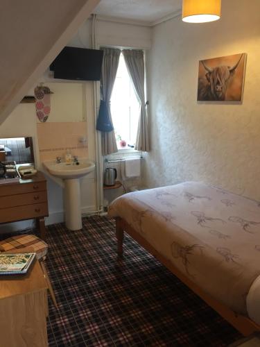 a bedroom with a bed and a sink and a window at Tanglin Guest House in Oban