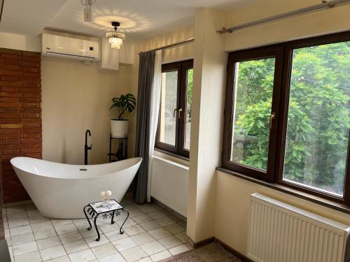 a bathroom with a tub in a room with windows at Wine Hills in Tbilisi City