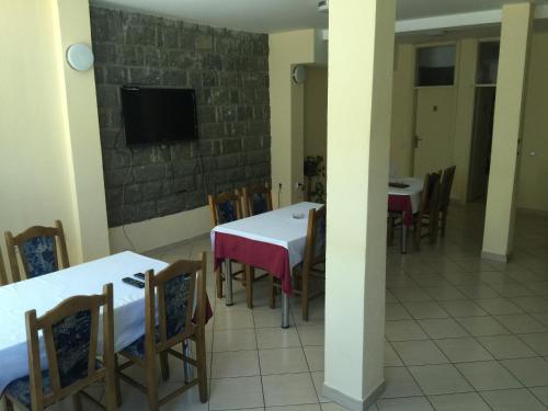 a dining room with tables and chairs and a flat screen tv at Bed & Breakfast Karavan in Raška