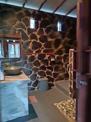 a kitchen with a wall covered in fake rocks at BINTANG MUNDUK in Munduk