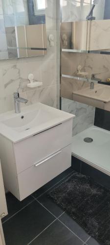 une salle de bain blanche avec un lavabo et un miroir dans l'établissement Residence Jannate paris, à Thiais