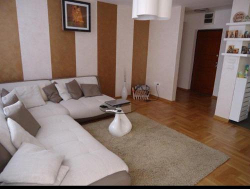 a living room with a white couch and a table at Lux Apartman 7 in Voždovac