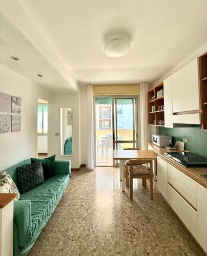 ein Wohnzimmer mit einem grünen Sofa und einem Tisch in der Unterkunft Appartamento luminoso vista mare in Lido di Jesolo