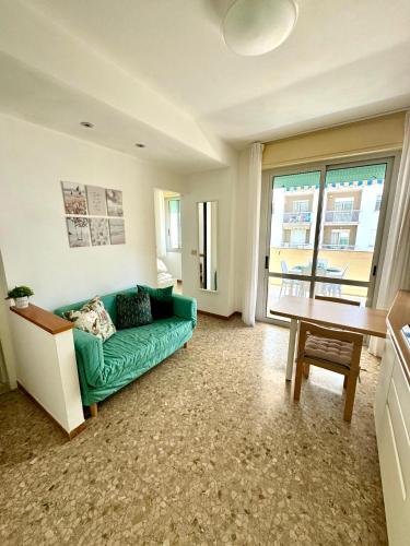 uma sala de estar com um sofá verde e uma mesa em Appartamento luminoso vista mare em Lido di Jesolo