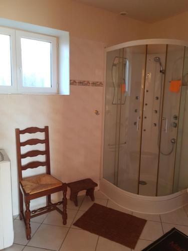 La salle de bains est pourvue d'une douche et d'une chaise en bois. dans l'établissement Les pommiers doux, à Lestre