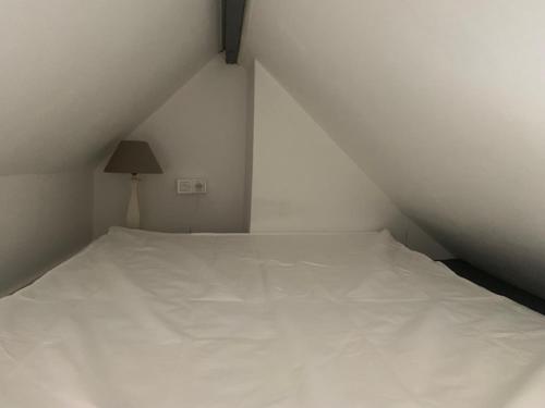 - un lit blanc dans une chambre blanche avec une lampe dans l'établissement Le studio de la plage !, à Dunkerque
