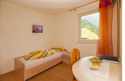 a bedroom with two beds and a table and a window at Gasthaus Jaufenblick in San Martino