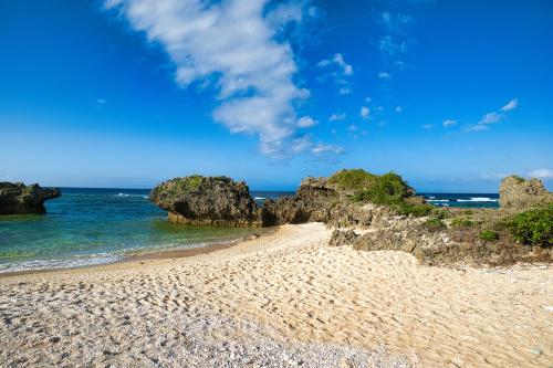 a sandy beach with rocks in the ocean at 松田テラスB Matsuda Terrace B in Matsuda