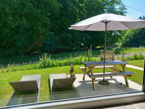 a picnic table and two chairs with an umbrella at The Bungalow, Forest of Dean in Coleford