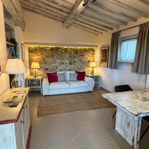 sala de estar con sofá blanco y pared de piedra en Podere Bellavista, en San Gimignano