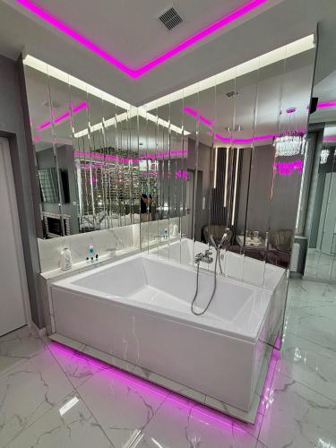 a large white tub in a bathroom with purple lights at Apartament "Prezydencki Deluxe" Centrum z dużą wanną dla Dwojga in Gniezno