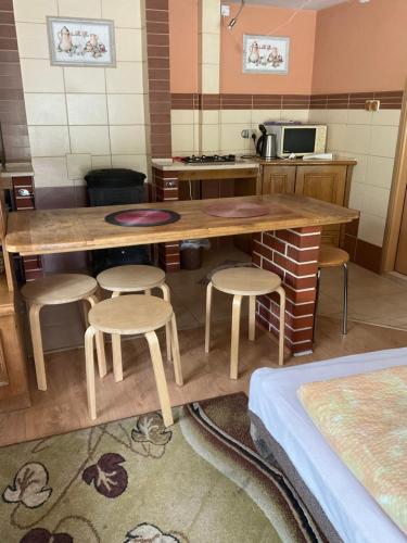 a kitchen with a large wooden table and stools at Jezioranka in Skorochów