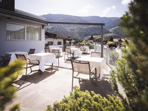 a patio with white tables and chairs and mountains at Hotel Panorama in Rablà