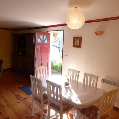 - une salle à manger avec une table, des chaises et une porte rouge dans l'établissement Gîte de la Chenardais, à La Boussac