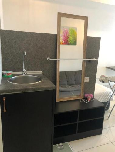 a bathroom with a sink and a mirror next to a bed at Aeropod 5 mins to Airport 10 mins to KK city in Kota Kinabalu