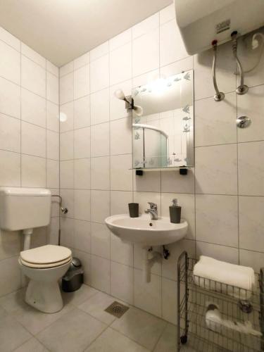 a white bathroom with a toilet and a sink at Rafael Apartments in Medulin