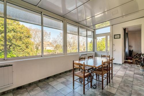 une salle à manger avec une table, des chaises et des fenêtres dans l'établissement Maison Familiale BERGERAC billard jardin clos, à Bergerac