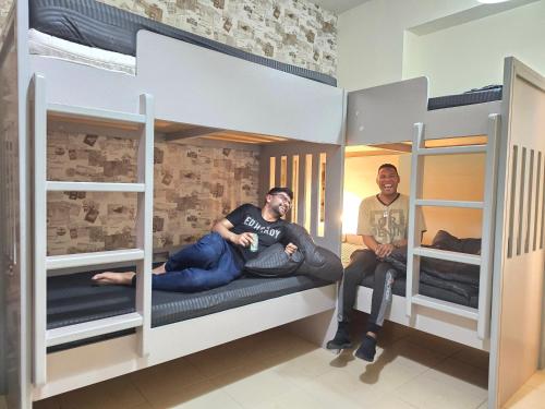 two men sitting in bunk beds in a room at 1 WORLD, Premium Hostel, JBR, Near Metro and Beach in Dubai