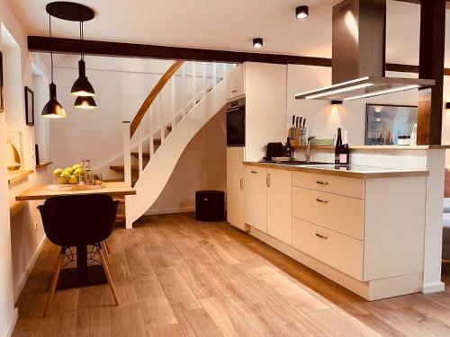 a kitchen with white cabinets and a staircase at Sommerhaus Reethaus "M" in Grödersby