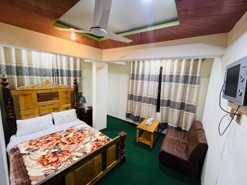 Blue Sky Hotel & Restaurant في سكردو: غرفة نوم بسرير واريكة وتلفزيون