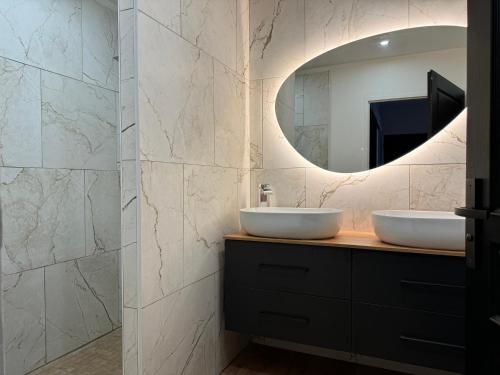 une salle de bain avec deux lavabos et un miroir dans l'établissement Villa la lagune piscine et spa privés 8 Couchages parking privé et borne de recharge électrique, au Barcarès