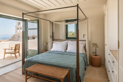 a bedroom with a canopy bed and a balcony at Patina Vivera Estate Santorini in Pirgos