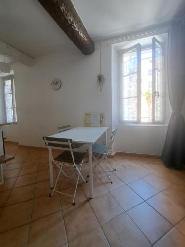 une table et des chaises blanches dans une chambre avec fenêtres dans l'établissement T2 Proche du port, zone piétonne, à Toulon