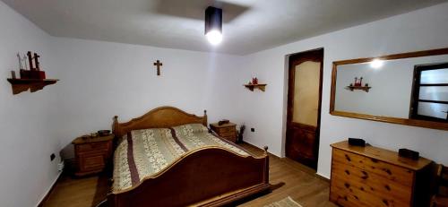een slaapkamer met een bed, een dressoir en een spiegel bij La Măcei in Cărbunari