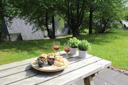 una mesa de picnic con copas de vino y comida. en L'Écureuil - Terrasses de Malmedy en Malmedy