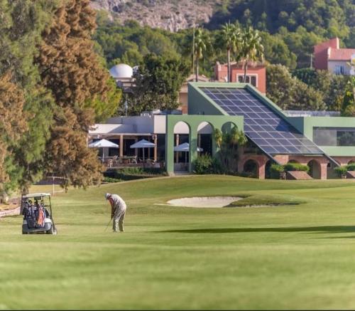 a man is playing golf on a golf course at Charming 3-storey house at residential golf resort in Muntanya la Sella