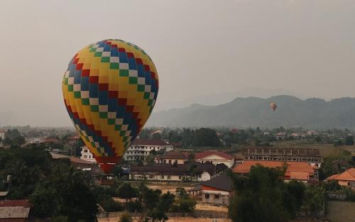 a colorful hot air balloon flying over a town at Mad Monkey Vang Vieng in Vang Vieng
