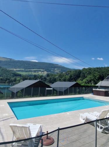 - une piscine avec 2 chaises blanches à côté dans l'établissement Chalet bord de lac avec piscine N2E, à Laffrey