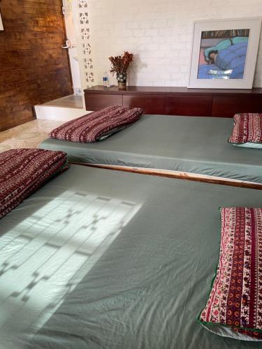 three beds in a room with green sheets and red pillows at Cọ cùn HomestayR3 single beds in Buon Ma Thuot
