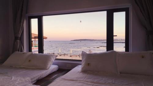 a bedroom with two beds and a view of the beach at Long Vĩ hotel - đảo Phú Quý in Cu Lao Thu